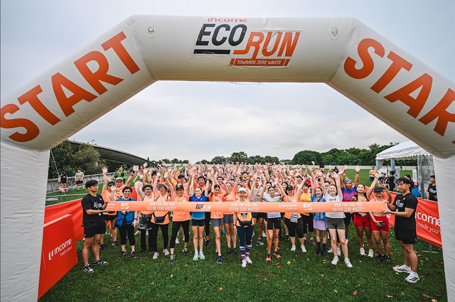 Joyful crowd at the start of "Income Eco Run" event, promoting zero waste.